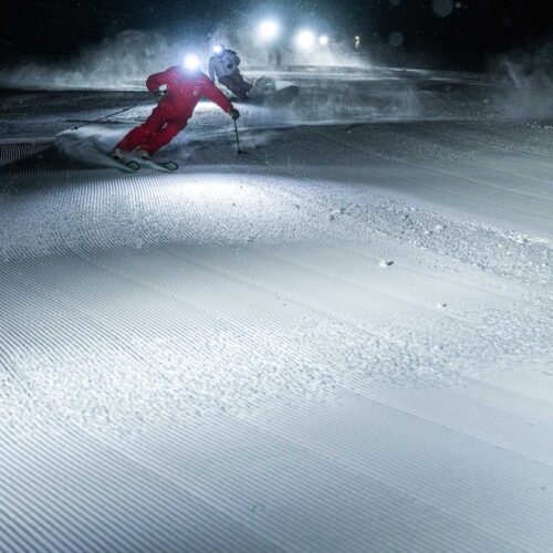 A group of people night skiing with headlamps at Big Sky Resort in Montana.