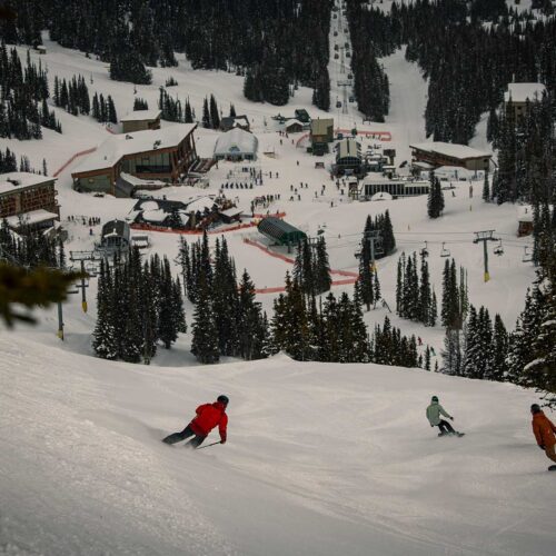 Les skieurs descendant la piste jusqu'au lodge et à la zone des remontées mécaniques à Banff Sunshine dans les Rocheuses canadiennes.