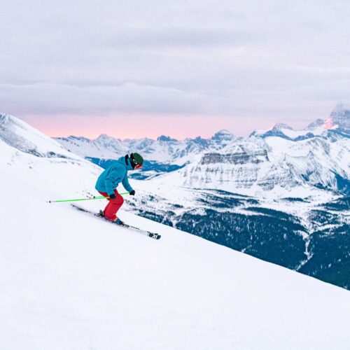 A skier in red and blue gear skiing a run at Banff Sunshine in the Canadian Rockies.