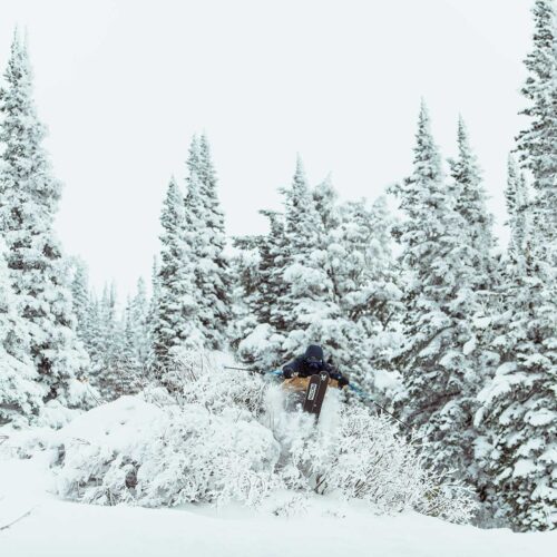 A skier getting some air through the snow covered glades at Grand Targhee Resort in Wyoming.