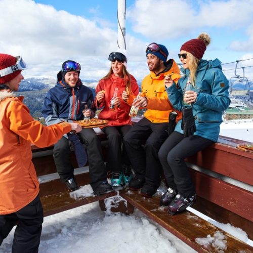 A group of friends enjoying some apres drinks and food on a lodge deck at Mt Buller in Australia.