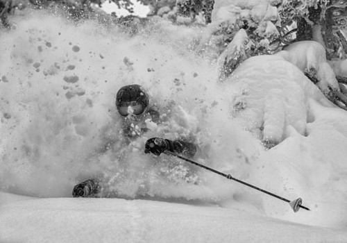 A skier skiing through deep powder on a collective trek with Mountain Collective.